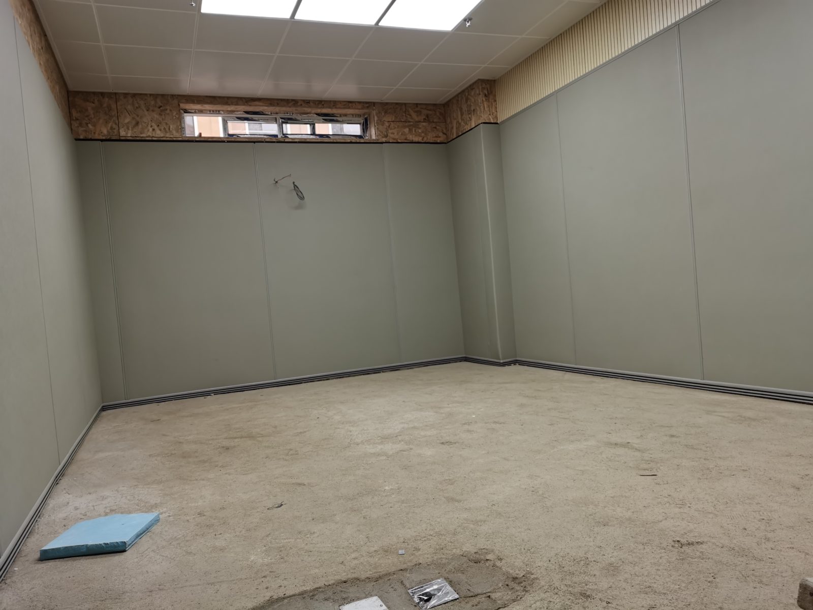 审讯室灰色防撞软包墙面整体安装实景,顶部搭配木条吸音板,高密度海绵软包防自伤设计