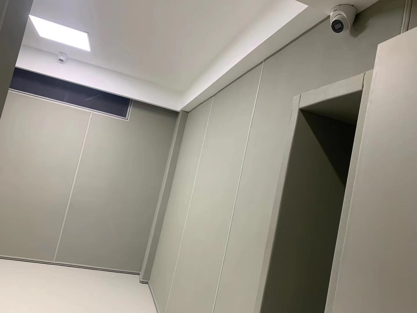 办案区审讯室浅灰防撞软包墙面整体实景,门框软包包边配监控摄像头,防自伤防撞设计